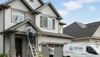 Technician cleaning residential gutters with safety gear in Tulsa, OK for vinyl siding protection